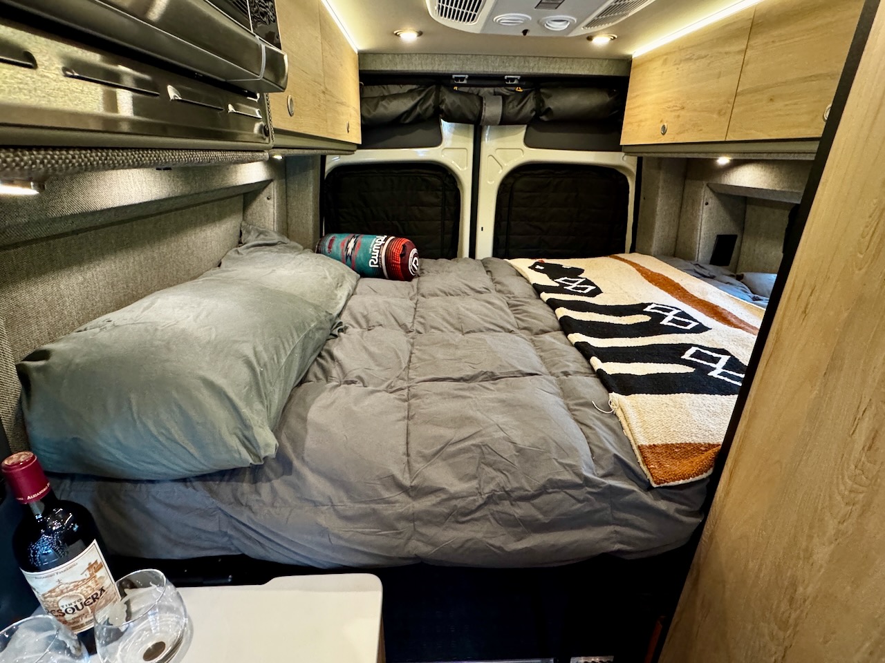 The rental van’s bed made up with fresh bedding and a Southwest throw